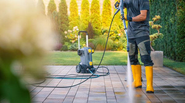 Homme nettoyant une terrasse avec un nettoyeur haute pression
