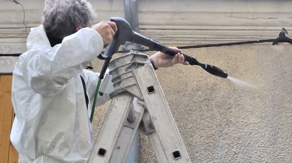 homme nettoyant une façade avec de l'eau à haute pression